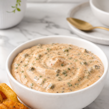 Creamy homemade Cajun remoulade sauce in a white bowl with fried shrimp and fries.