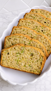 Close view of tender zucchini bread slices showing green zucchini flecks and golden crust.