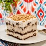 Ice cream sandwich cake slice with toffee bits on a clean plate and bright kitchen wallpaper.
