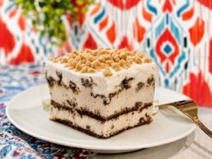 Ice cream sandwich cake slice with toffee bits on a clean plate and bright kitchen wallpaper.