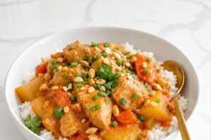 Slow cooker Massaman chicken curry served over jasmine rice in a white bowl.