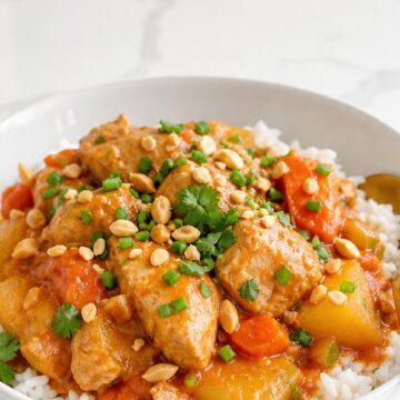 Slow cooker Massaman chicken curry served over jasmine rice in a white bowl.