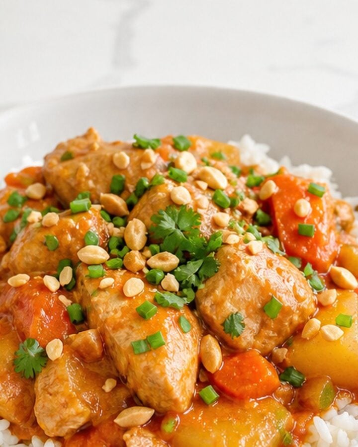 Slow cooker Massaman chicken curry served over jasmine rice in a white bowl.