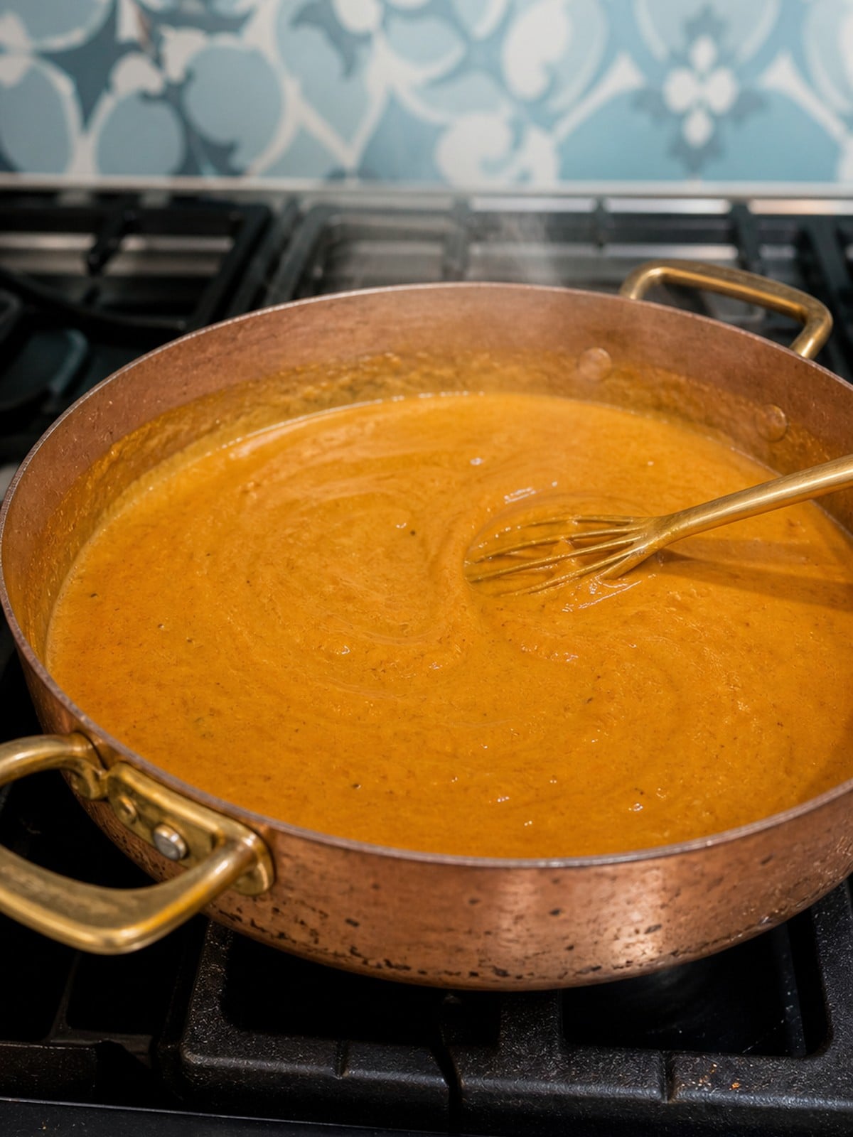 Creamy orange Massaman curry sauce simmering in a copper skillet.