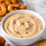 Finished Cajun remoulade sauce served with fried shrimp, hush puppies, and fried green tomatoes.