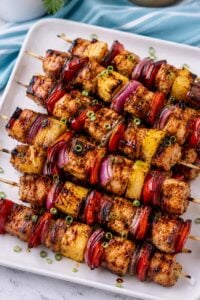 Grilled Hawaiian chicken skewers with pineapple, red bell pepper, red onion, and glossy Huli-Huli glaze on a white platter.