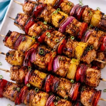 Grilled Hawaiian chicken skewers with pineapple, red bell pepper, red onion, and glossy Huli-Huli glaze on a white platter.