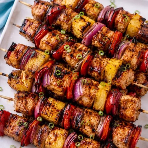 Grilled Hawaiian chicken skewers with pineapple, red bell pepper, red onion, and glossy Huli-Huli glaze on a white platter.