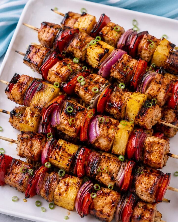 Grilled Hawaiian chicken skewers with pineapple, red bell pepper, red onion, and glossy Huli-Huli glaze on a white platter.