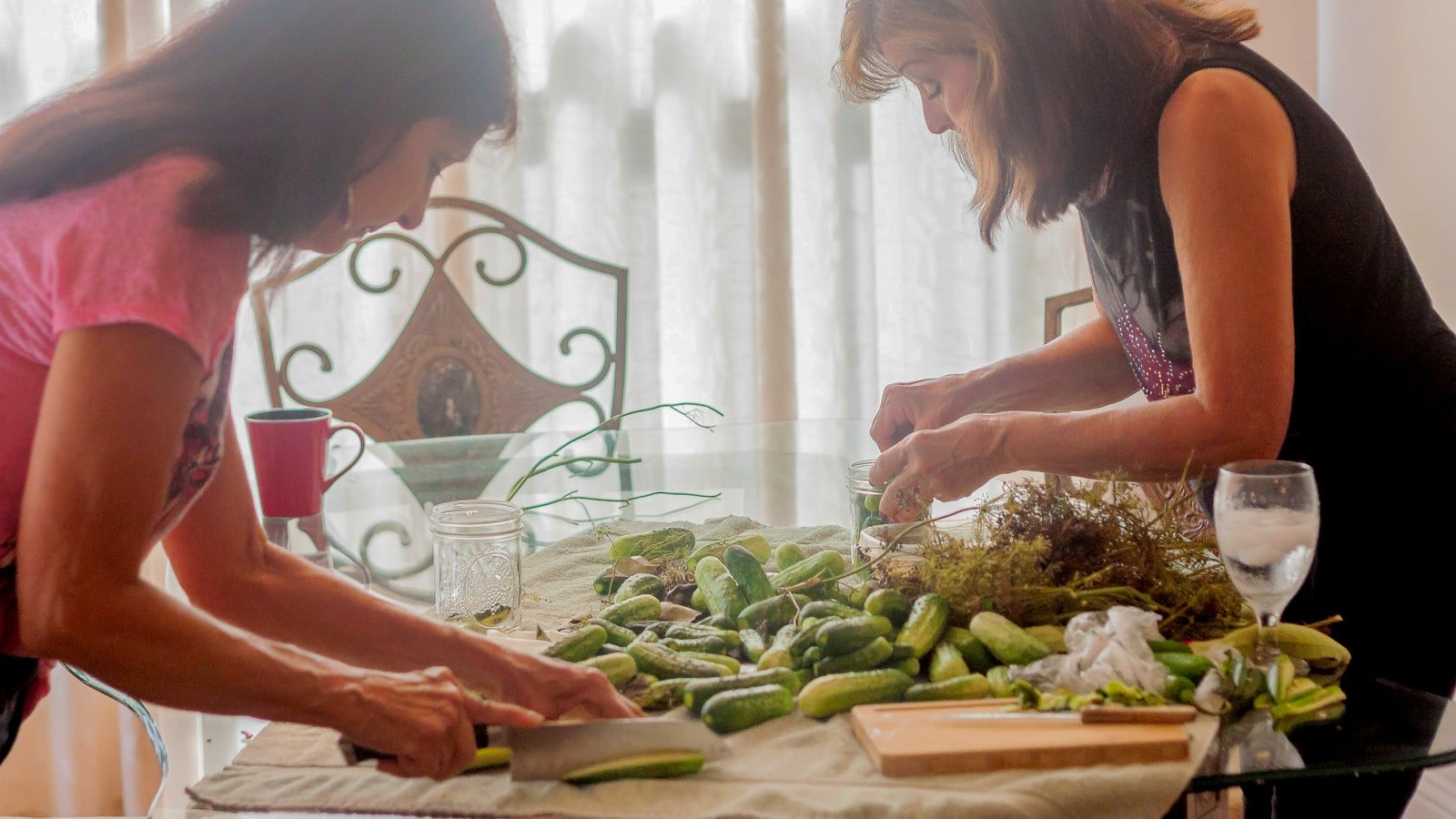 Family preparing cucumbers together at the table for old-fashioned dill pickles