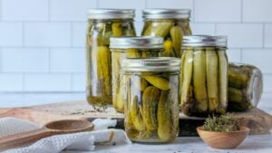 Quart jars of homemade garlic dill pickles with dill and spices on a kitchen counter
