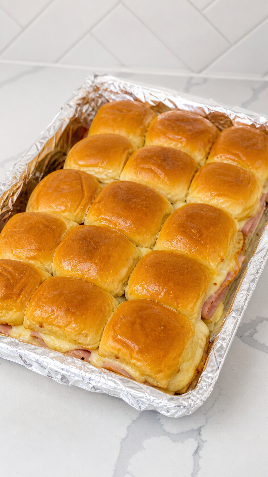 Baked Monte Cristo sliders in a foil-lined pan before powdered sugar is added.