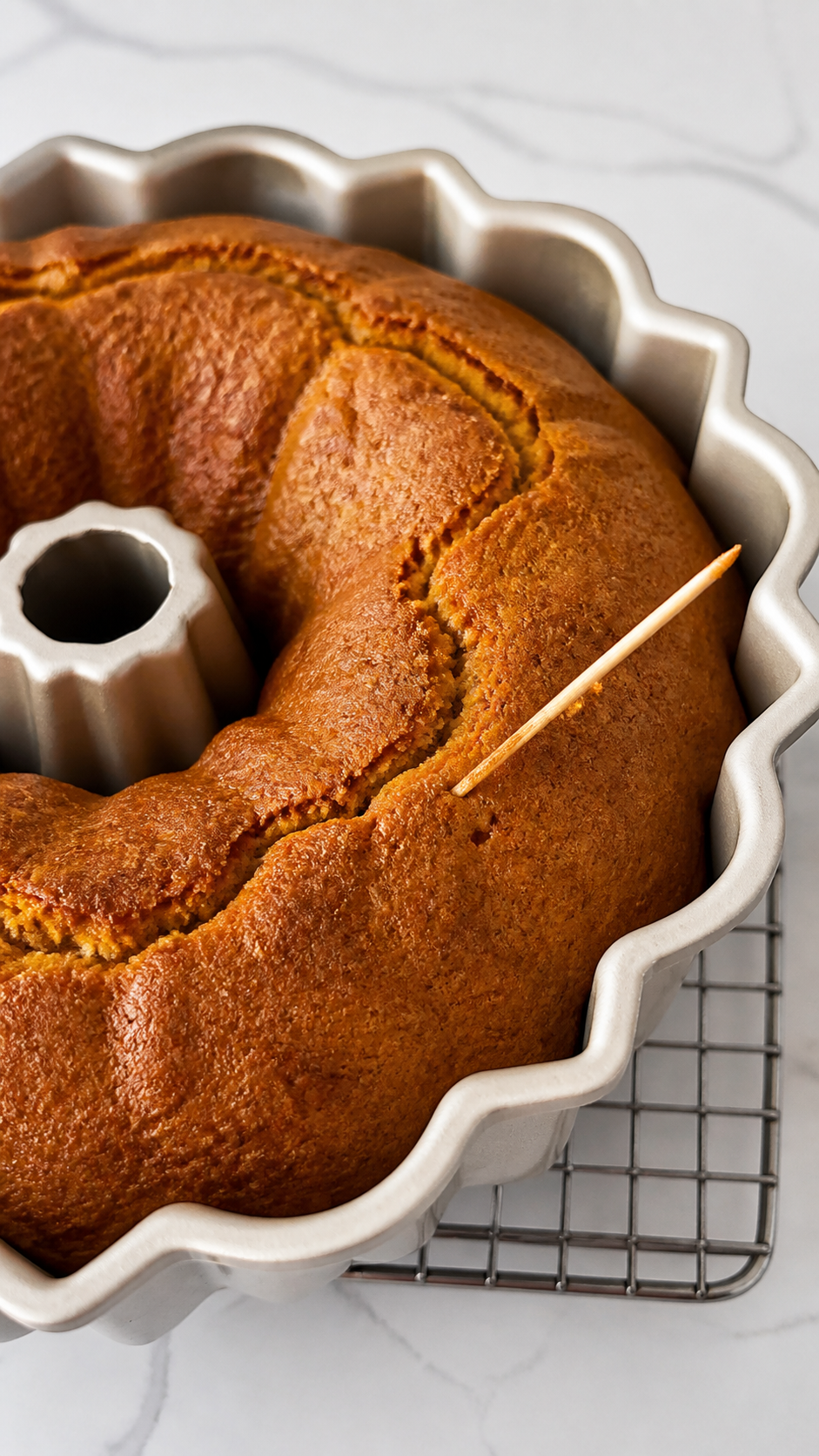 Baked pumpkin Bundt cake in the pan with a toothpick doneness check