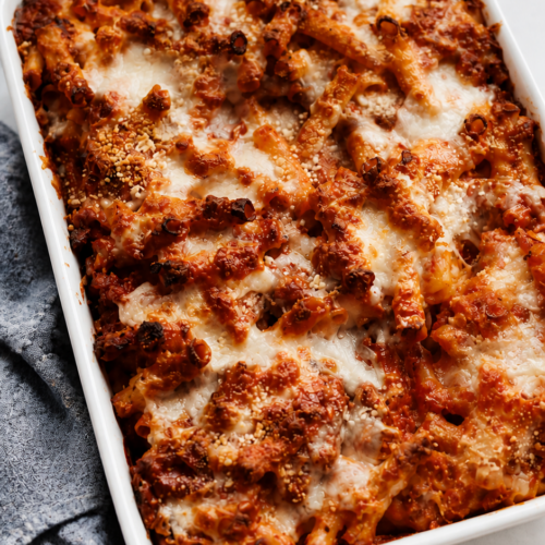 Baked ziti bubbling at the edges with melted lightly browned cheese.