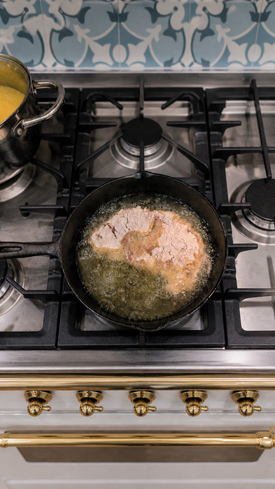 Breaded chicken fried steak frying in hot oil on the first side in a cast-iron skillet.