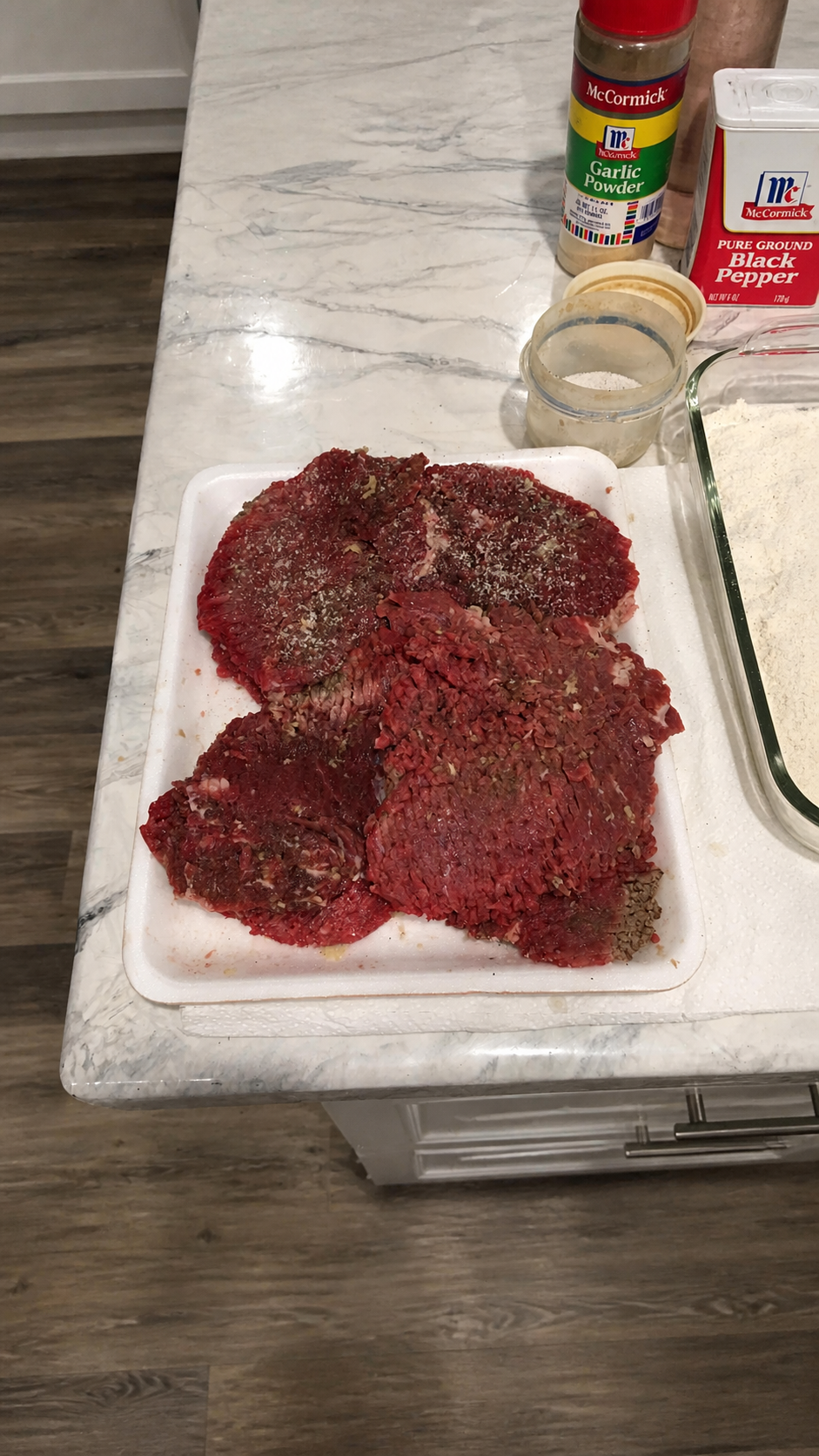 Tenderized beef steaks seasoned with minced garlic, seasoned salt, and black pepper.
