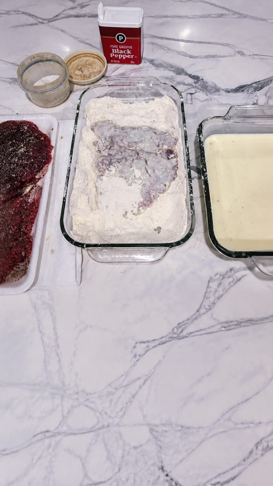 Steak pressed firmly into seasoned flour for a thick, craggy second coating.