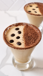 Close-up frothy Baileys espresso martini with grated dark chocolate and coffee beans.