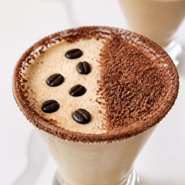 Close-up frothy Baileys espresso martini with grated dark chocolate and coffee beans.