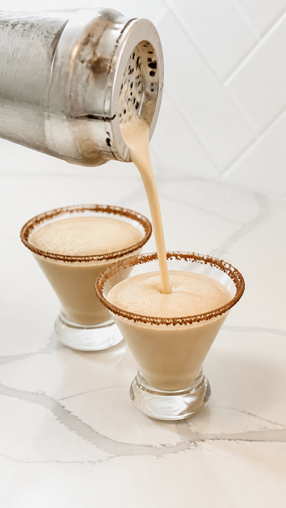 Frothy creamy espresso martini strained into two chocolate-rimmed glasses.
