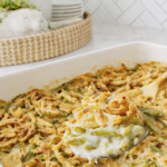 Crunchy green bean casserole with creamy green beans and golden French fried onions in a white baking dish.