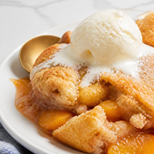 Rustic Bisquick peach cobbler with juicy peaches, golden topping, melting vanilla ice cream, and a plain white plate.