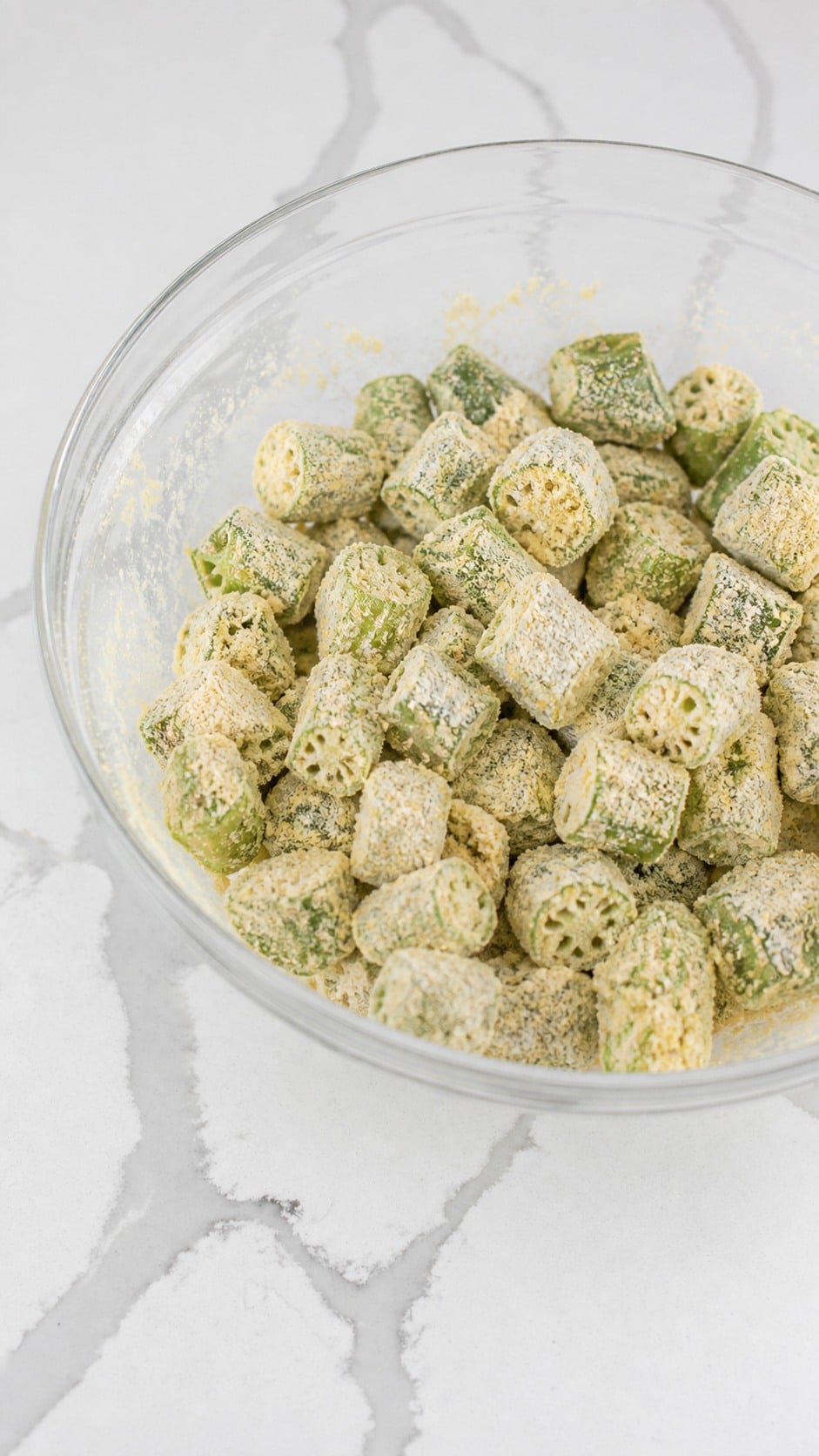 Buttermilk-coated okra rounds thoroughly covered in seasoned cornmeal and flour.
