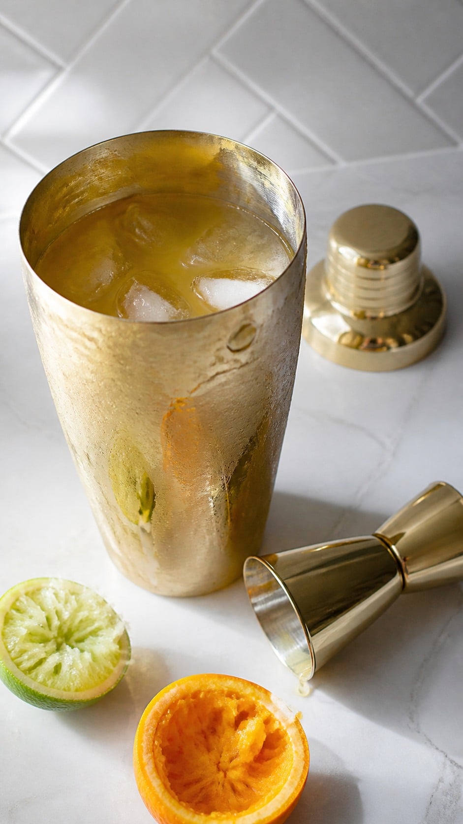 Tequila, Cointreau, citrus juices, olive brine, and simple syrup combined with ice in a cocktail shaker.