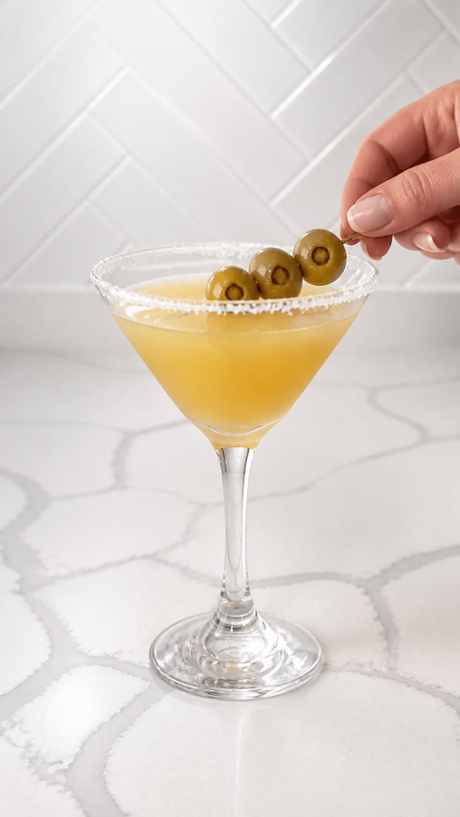Three jalapeño-stuffed olives placed across a finished Mexican martini.