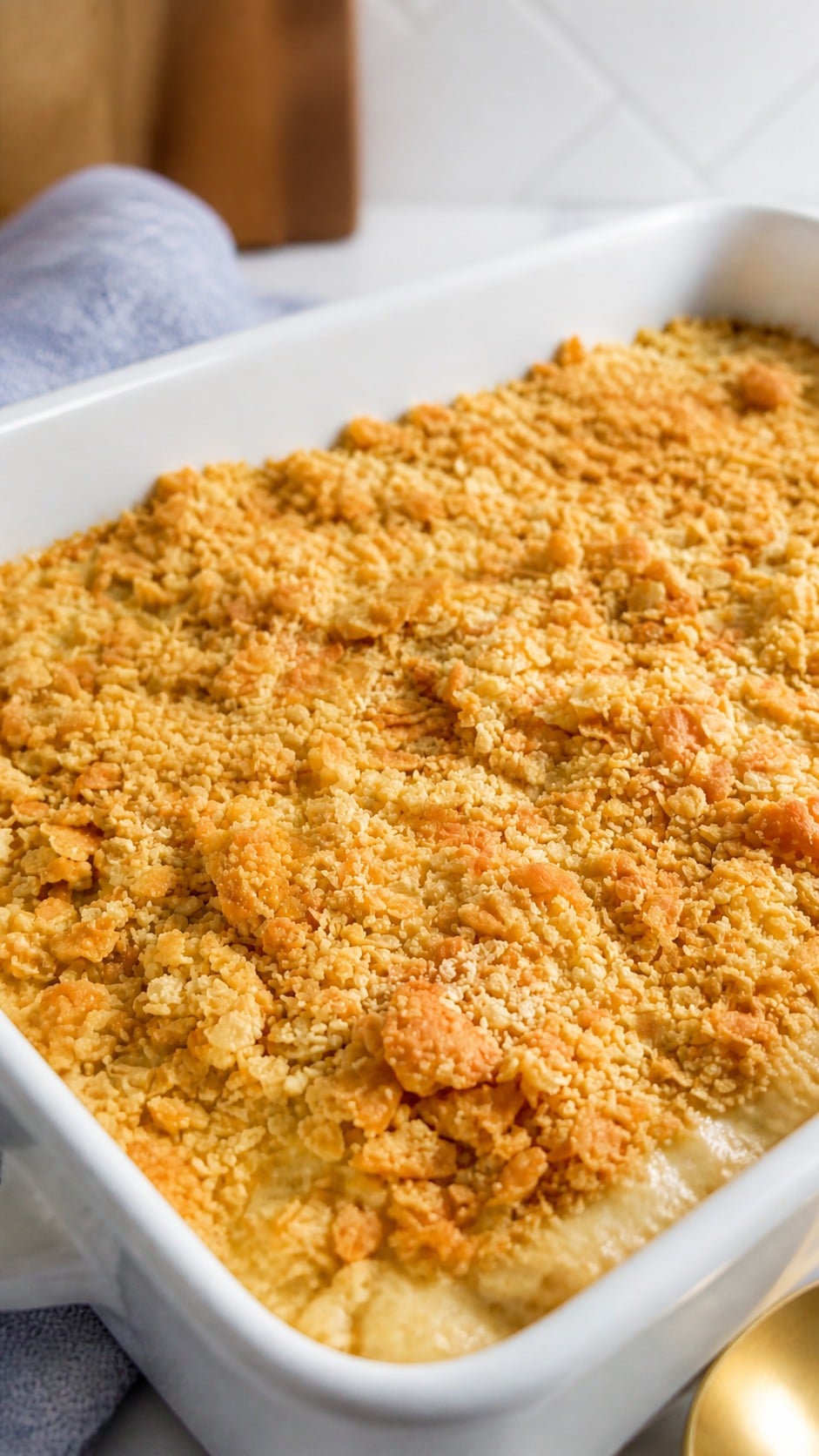 Close angled view of creamy chicken and rice casserole beneath crisp golden cracker crumbs.