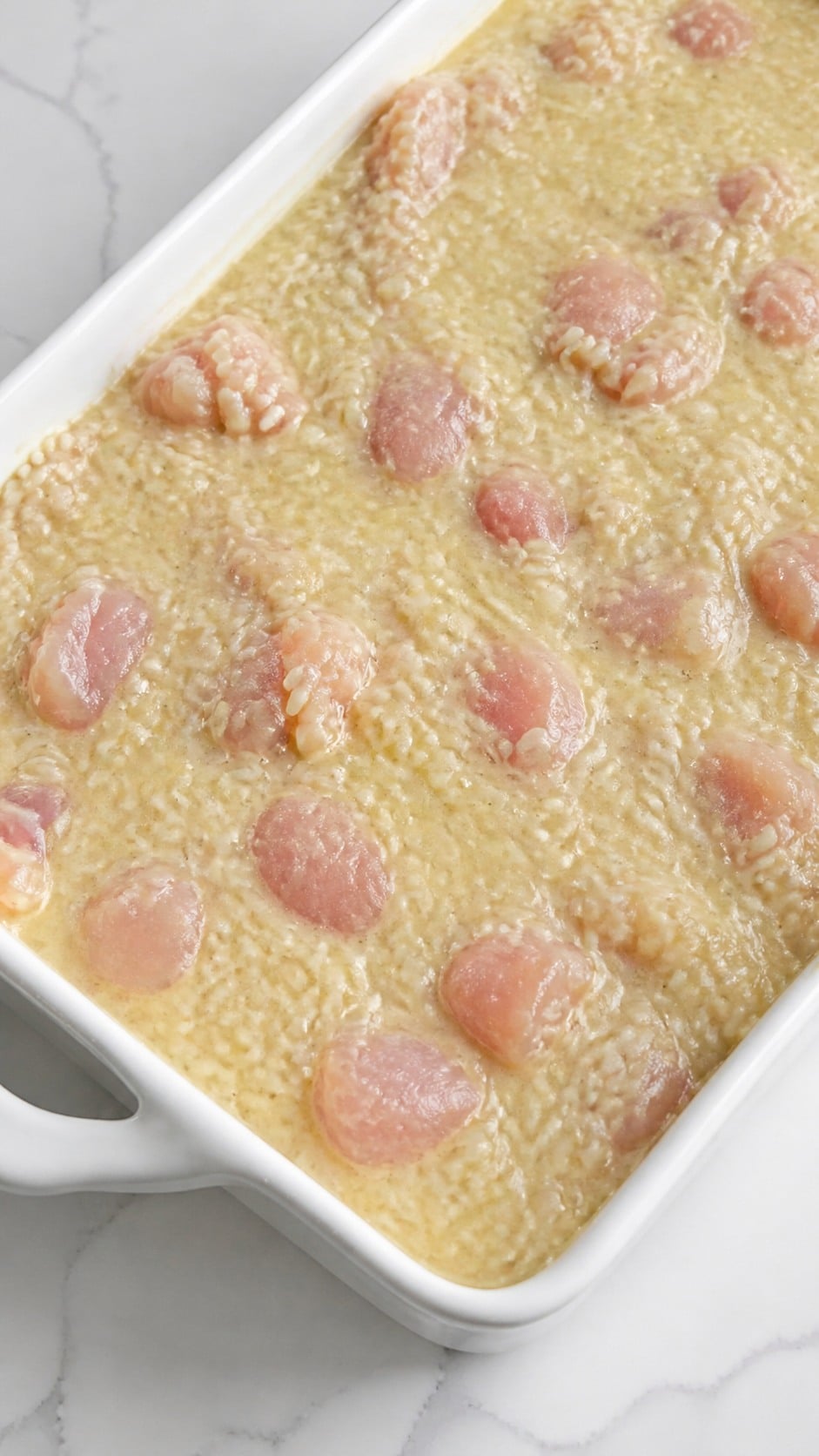 Cubed chicken, uncooked parboiled rice, water, and condensed soups stirred together in a baking dish.