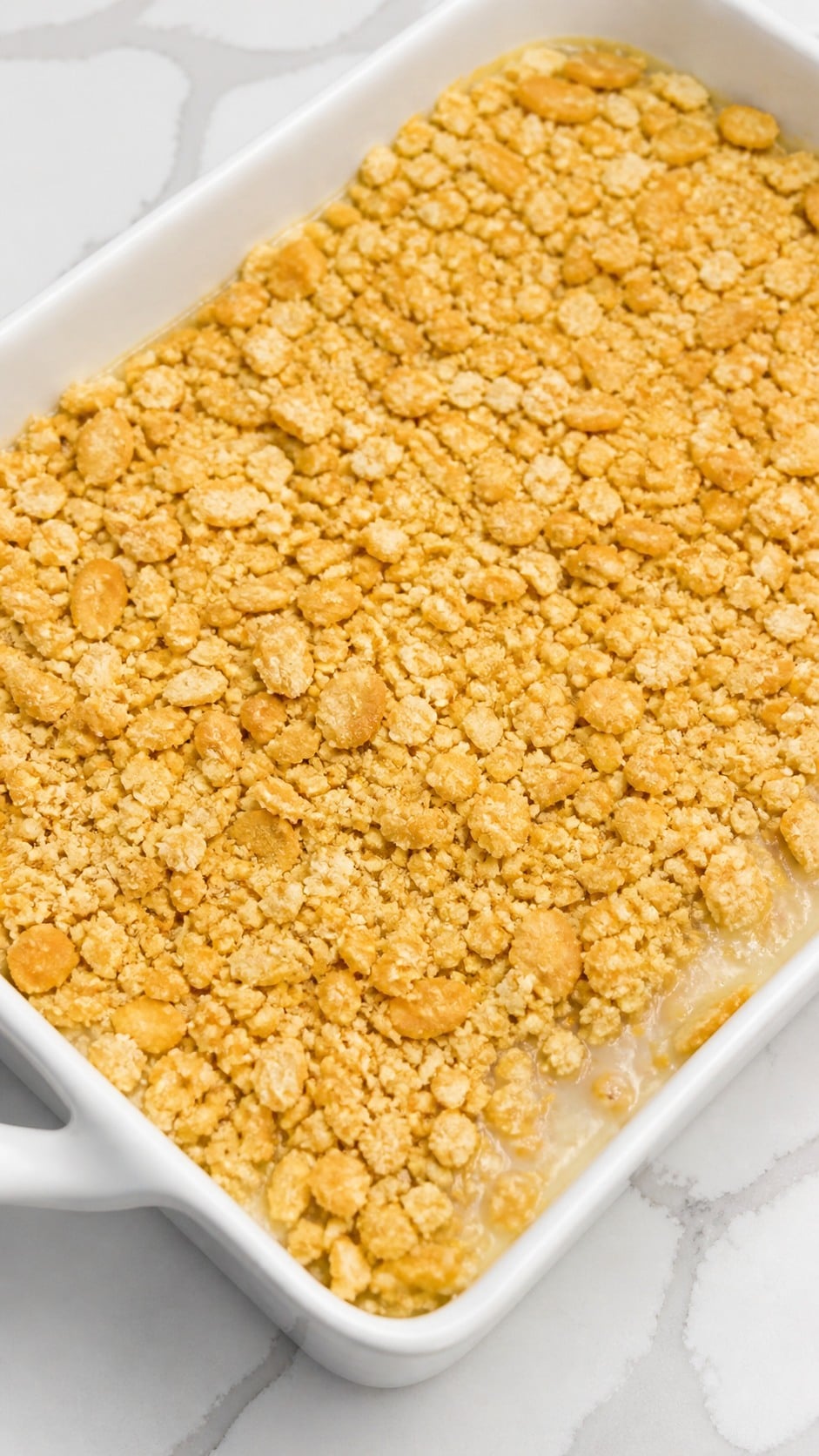 Buttered Ritz cracker crumbs spread evenly over unbaked chicken and rice casserole.