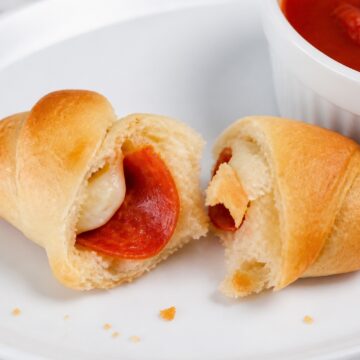 Pepperoni pizza crescent roll torn open to show mozzarella and pepperoni.