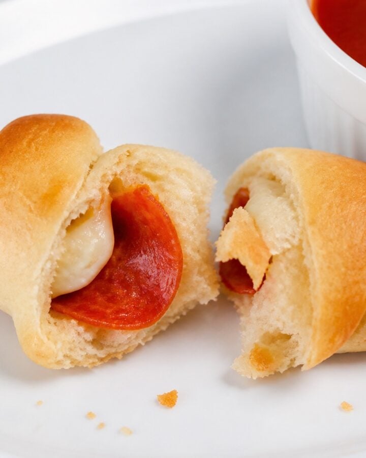 Pepperoni pizza crescent roll torn open to show mozzarella and pepperoni.