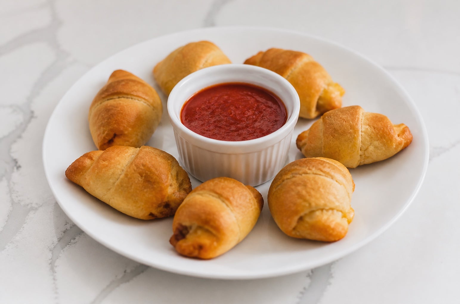 Pepperoni pizza crescent rolls arranged around warm marinara sauce.