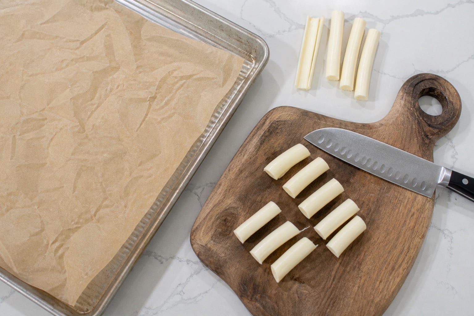 Prepared baking sheet and mozzarella string cheese cut into thirds for pizza crescent rolls.