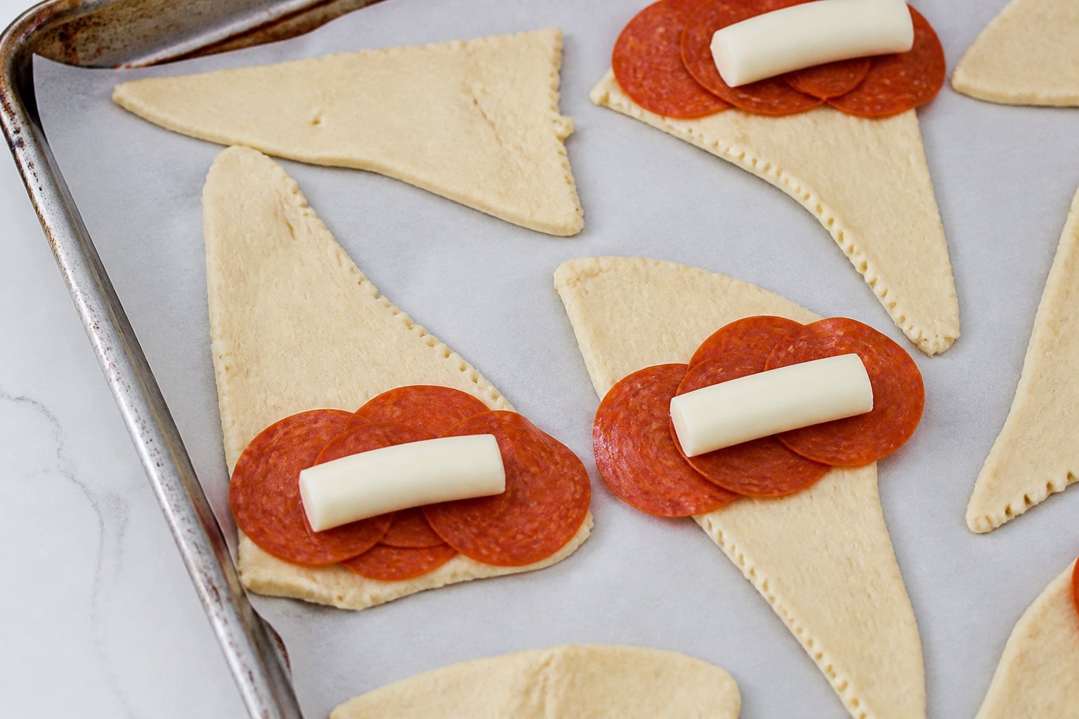 Pepperoni slices and mozzarella placed on crescent dough triangles.