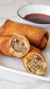 Pork egg roll cut open to show sausage, cabbage, carrot, mushroom, and water chestnut filling.