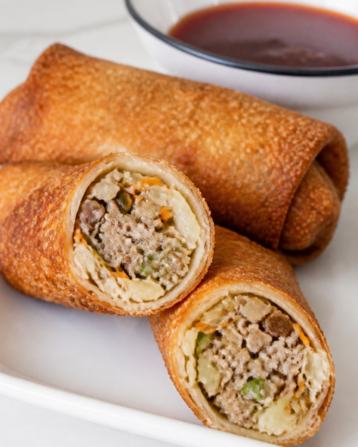 Pork egg roll cut open to show sausage, cabbage, carrot, mushroom, and water chestnut filling.