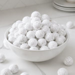 Powdered sugar cranberries piled in a white bowl on a bright kitchen counter.