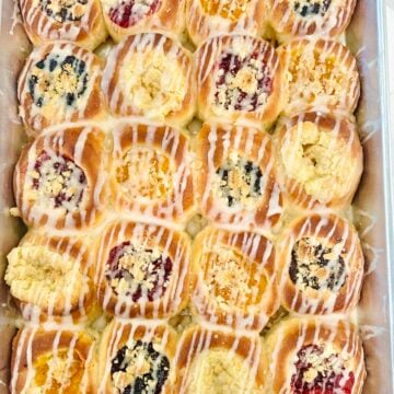 Overhead pan of homemade Texas Czech kolaches with assorted fruit, poppy seed, cream cheese, posypka, and vanilla icing.