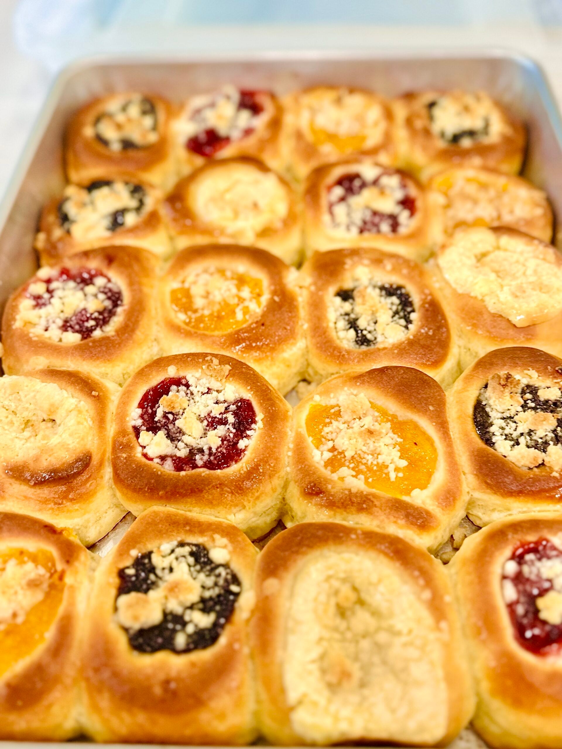 Close-up of golden Texas Czech kolaches with cherry, apricot, poppy seed, and cream cheese fillings.