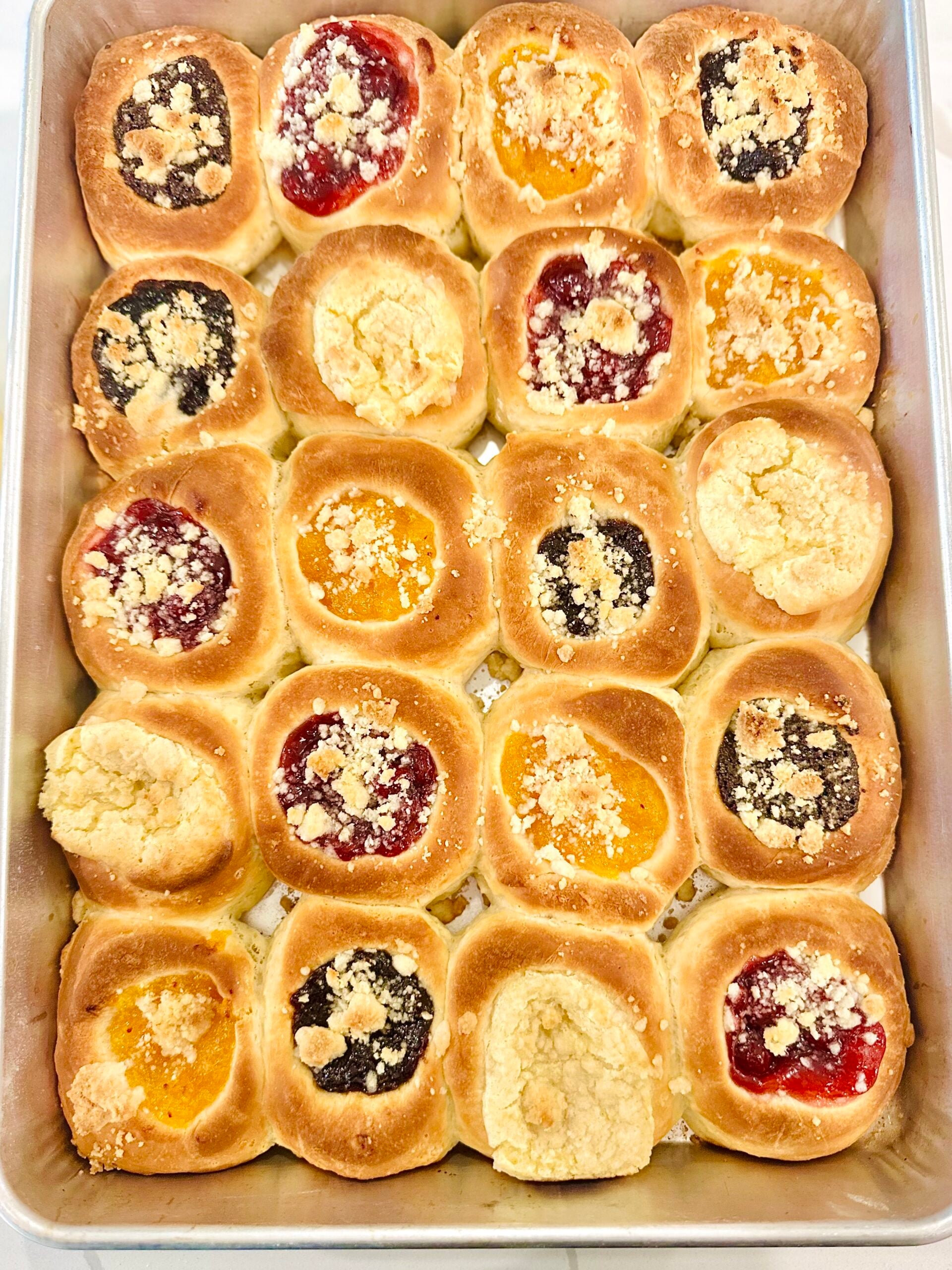Overhead pan of freshly baked Texas Czech kolaches with assorted fillings and posypka before icing.