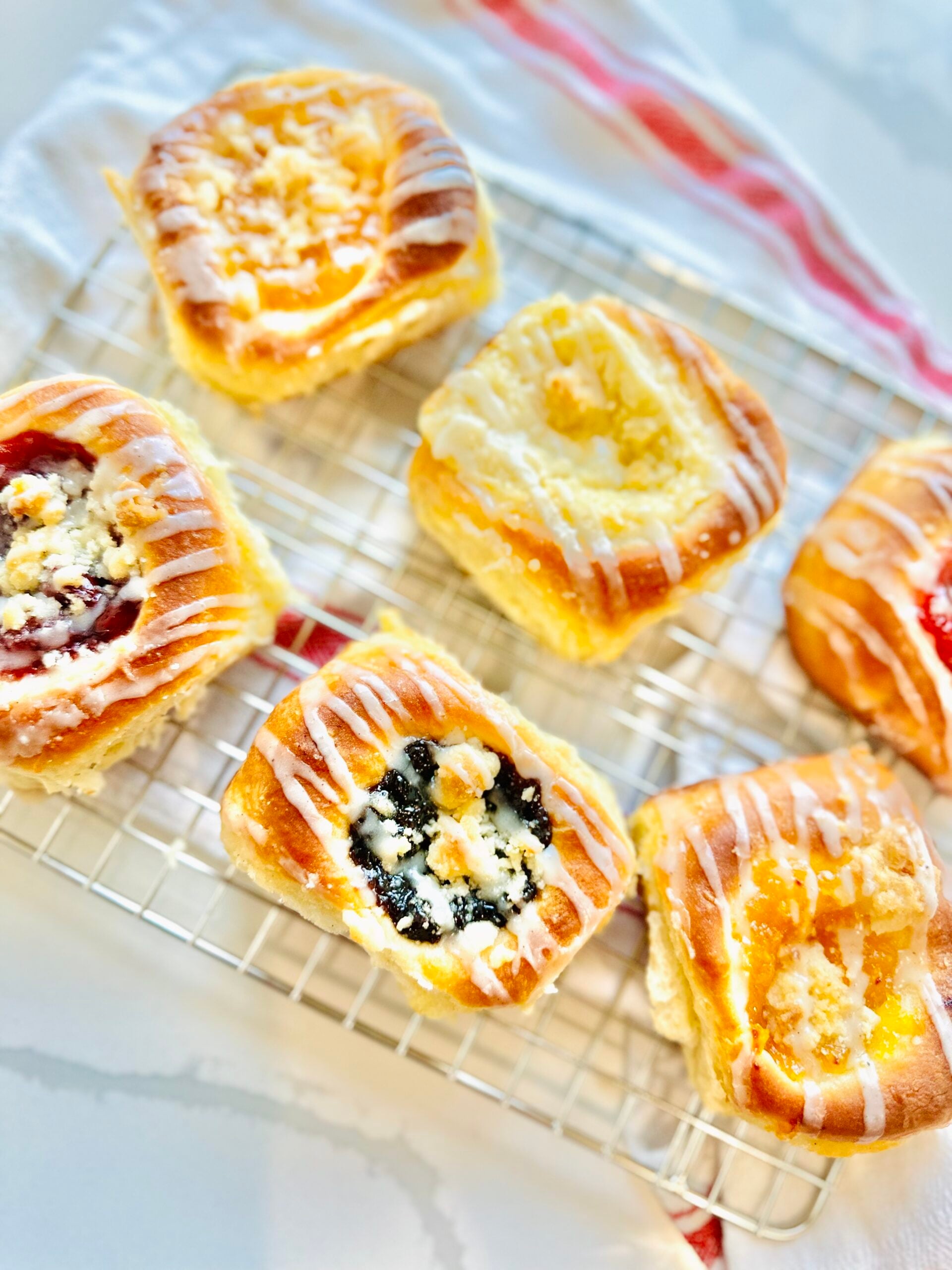 Overhead view of assorted iced Texas Czech kolaches arranged on a cooling rack.