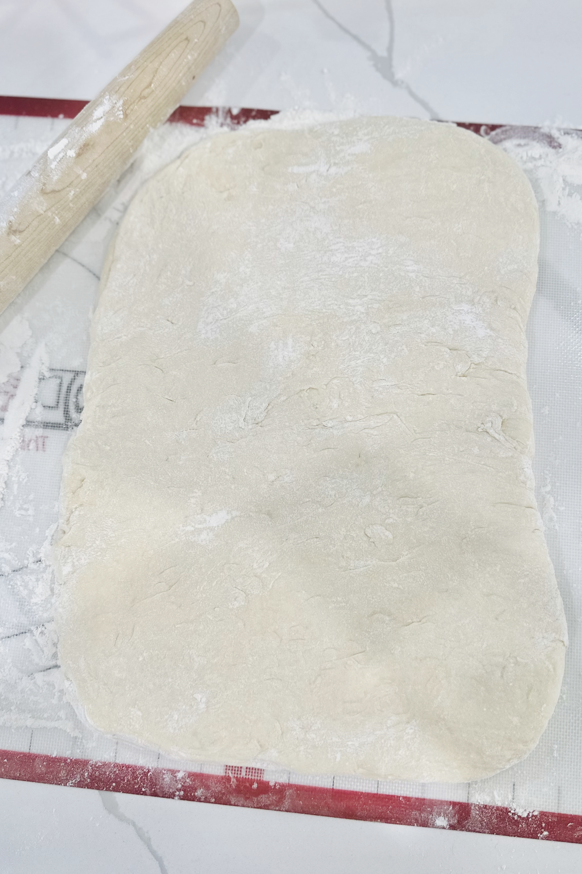 Enriched kolache dough rolled into a thick rectangle on a floured pastry mat.