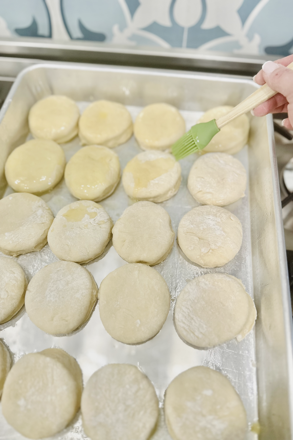 Cut kolache dough rounds brushed with melted butter on a baking sheet.
