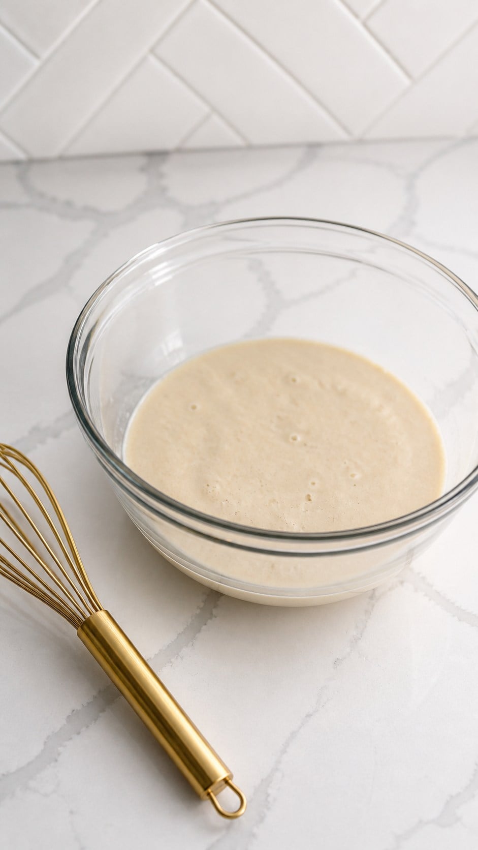 Freshly mixed poolish for wood-fired pizza dough in a clear bowl.
