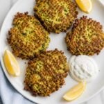 Warm zucchini fritters served with lemon dill sauce and lemon wedges.
