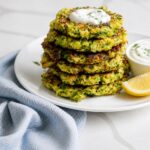 Stack of crispy zucchini fritters with deeply browned edges and visible zucchini shreds.