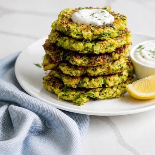 Stack of crispy zucchini fritters with deeply browned edges and visible zucchini shreds.